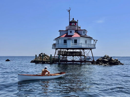 A man rows a Chester Yawl near Thomas Point Lighthouse