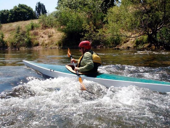 Paddling a Chesapeake 17LT wooden kayak with white hull and blue deck, built by Tim S., through a patch of whitewater