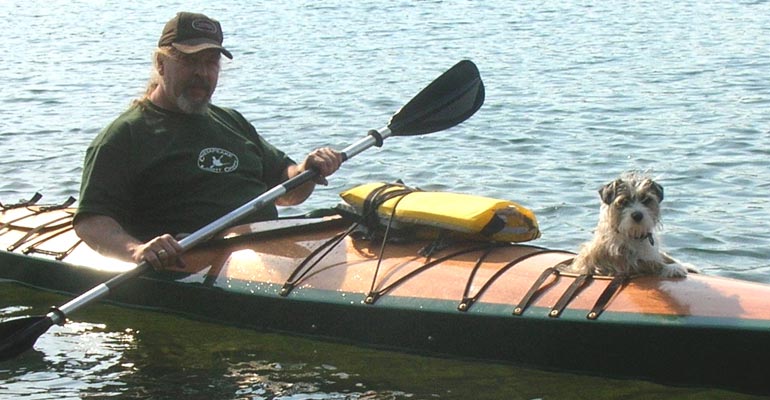 Jim T paddling his Chesapeake 18 wooden kayak with his furry first mate riding in the forward hatch