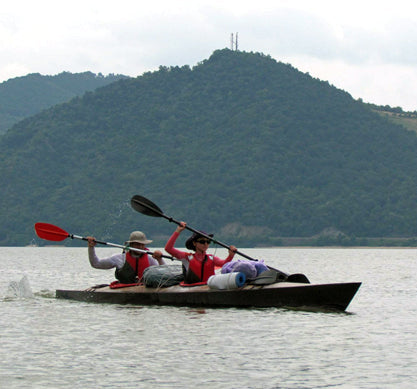 On the Danube River in Romania, two adventurers paddle a fully loaded Chesapeake Double wooden kayak built by Nur K.