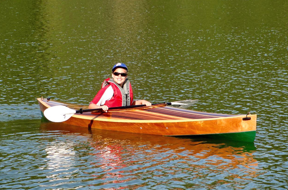 Kim F. sent in this image of her son happily paddling the Wood Duck 12 Hybrid kayak that he built with his dad.