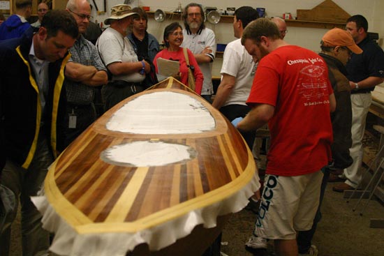 Applying fiberglass to the deck of a Wood Duck Hybrid kayak at a seminar