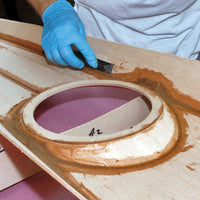 boatbuilder filleting seams on the underside of a stitch-and-glue kayak deck.