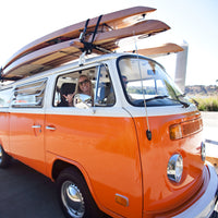 Vintage VW Bus transporting multiple Stand-up Paddleboards on roof racks.