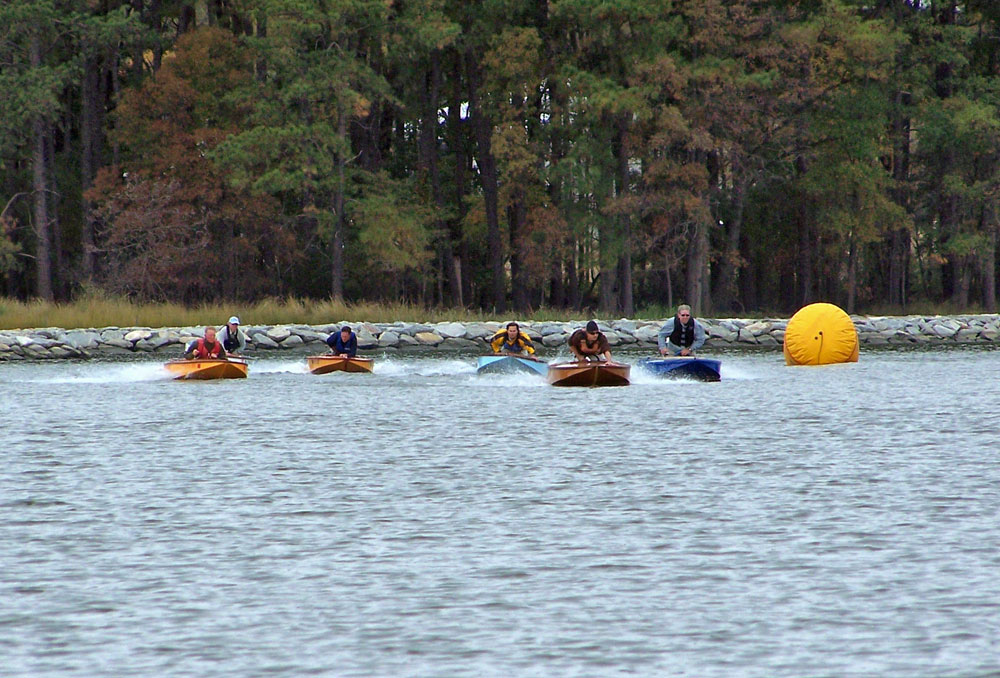 Drivers crouch over to increase the speed of Cocktail Class Racers. Aaron McWain, in the second boat from the right has taken the lead.