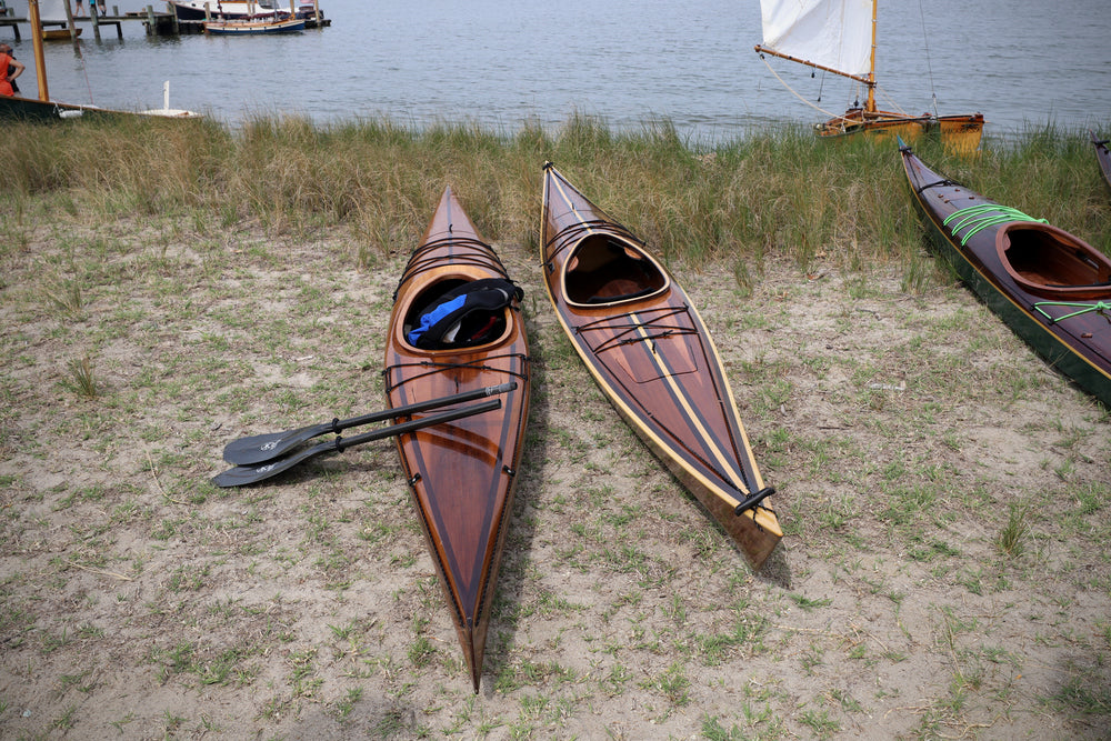 A microBootlegger Sport wooden kayak built by Dan T. (left) next to his Shearwater 17 Hybrid, onthe waterfront at the 2021 Big Little Boat Festival