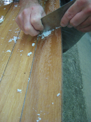 Scraping and smoothing the epoxy on the hull of an Annapolis Wherry Tandem kit.