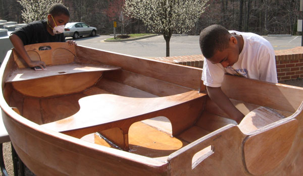 Calverton school students scraping and sanding the finish on their Eastport Pram.