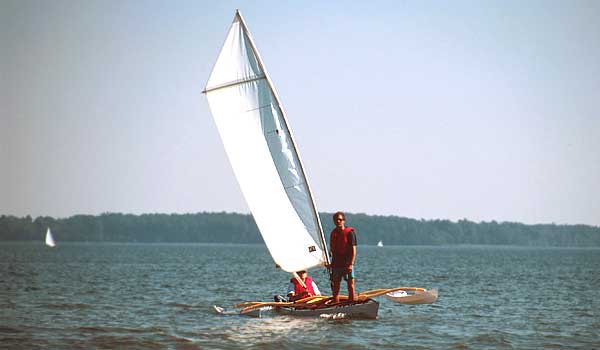 The CLC SailRig adds great stability to a canoe or kayak as seen in this image of a man standing up in a tandem kayak while it is under sail.