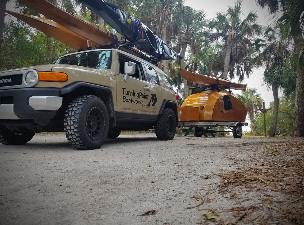 Turning Point  Boatworks hauling a CLC Teardrop Camper and carrying four kayaks at Fort Desoto Park in Florida.