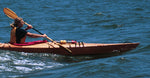 A woman catching a wave in a wooden Chesapeake 16 kayak Thumbnail