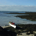 Roger W.'s Chesapeake 16 wooden kayak built by Roger W. beached on a rocky shore Thumbnail