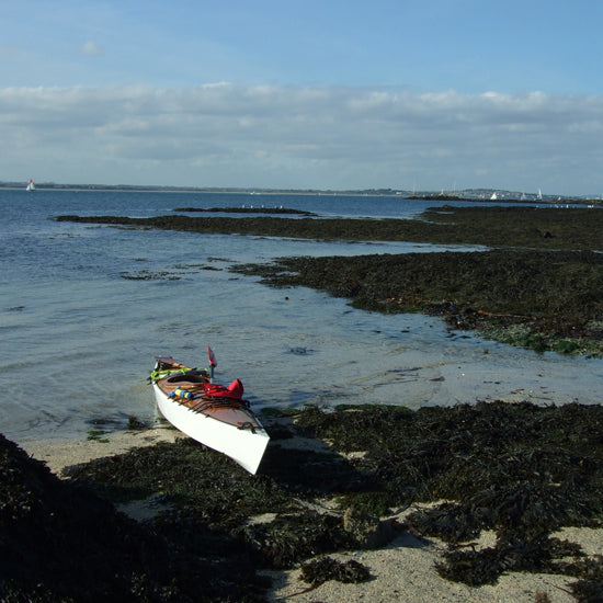 Roger W.'s Chesapeake 16 wooden kayak built by Roger W. beached on a rocky shore