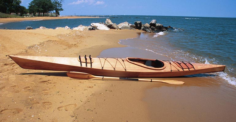A Chesapeake 16 wooden kayak beached at Sandy Point State Park on the Chesapeake Bay
