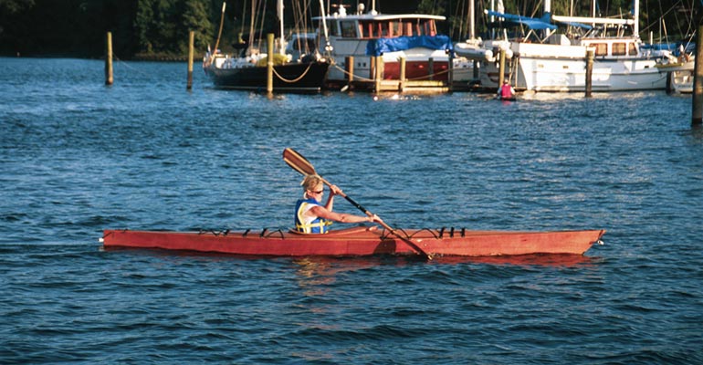 Paddling a Chesapeake 16 wooden kayak in front of a marina on a river