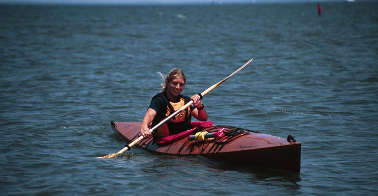 A woman enjoying a paddle in a Chesapeake 16 wooden kayak on the Chesapeake Bay