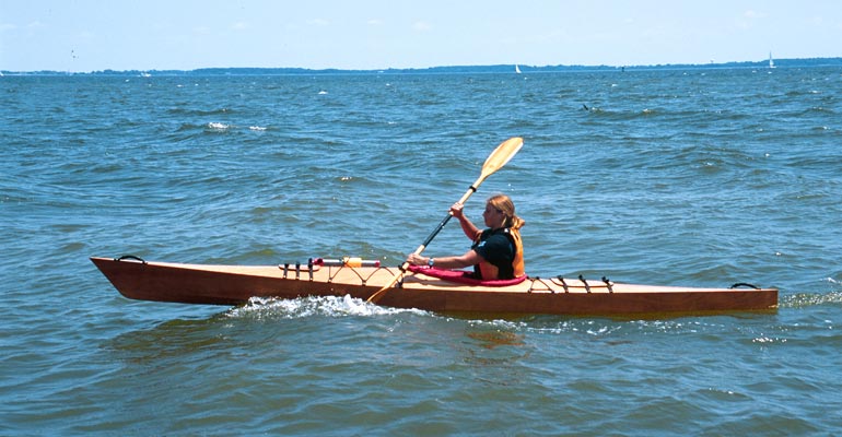 A woman paddling a Chesapeake 16 wooden kayak on the Chesapeake Bay