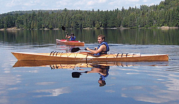 Paddling a Chesapeake 16 wooden kayak on a wooded lake