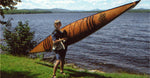 A youngster carrying a Chesapeake 16 wooden kayak Thumbnail