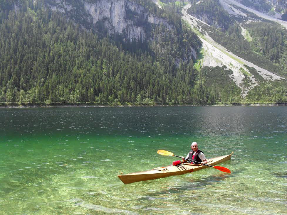 Paddling on a crystal clear mountain lake in Hungary in a Chesapeake 16 wooden kayak