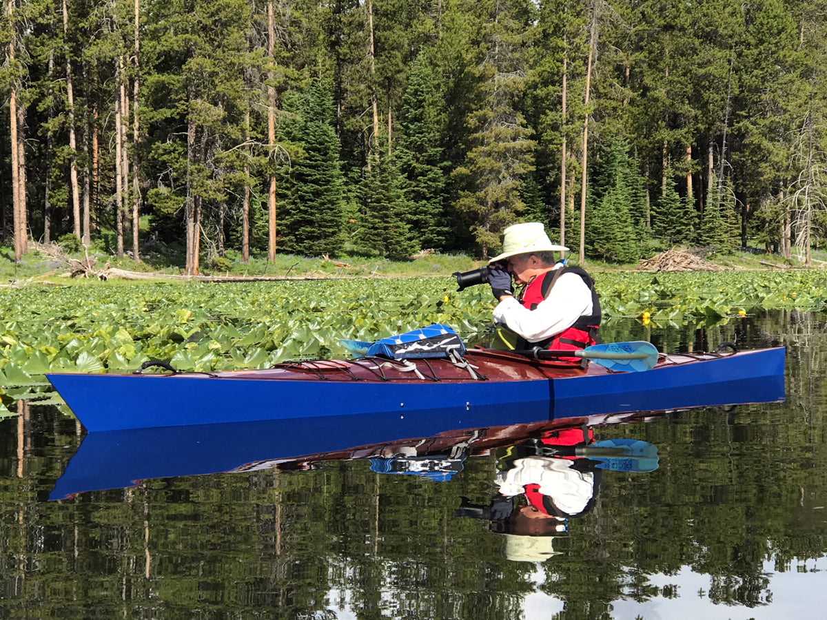 A man taking photos on Heron Pond in Grand Teton National Park, WY, from a Chesapeake 16 wooden kayak built by Mike B.