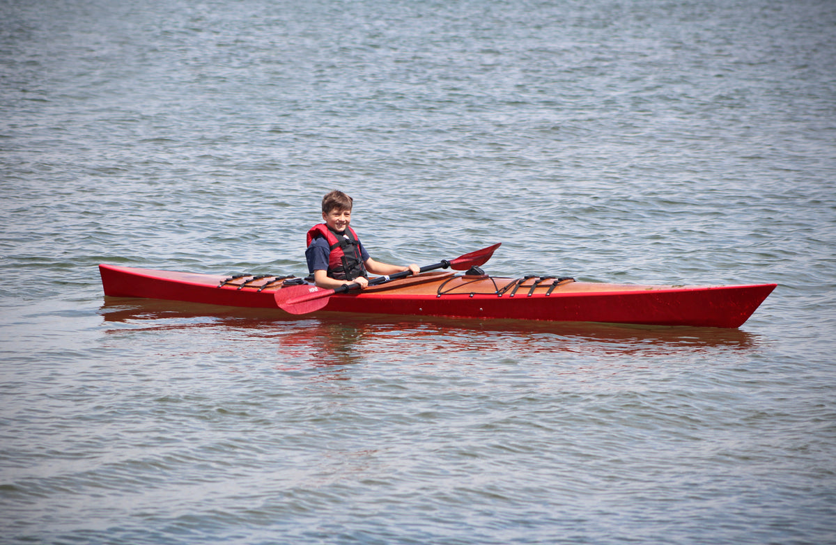 A youngster paddling a Chesapeake 16 wooden kayak at CLC's 2016 OkoumeFest 