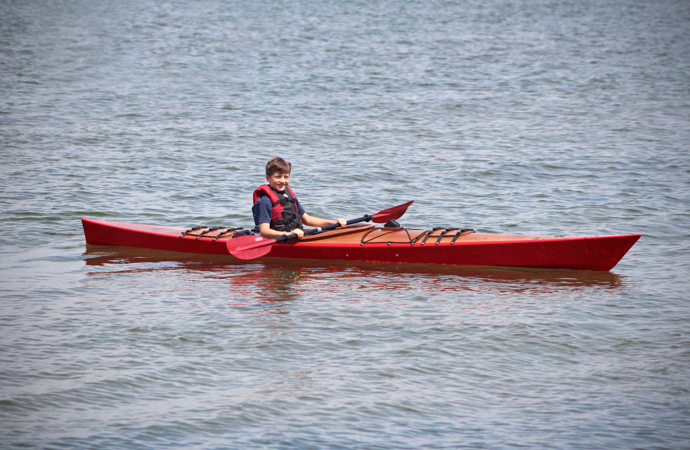 A youngster paddling a Chesapeake 16 wooden kayak at CLC's 2016 OkoumeFest 