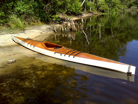 A white-hulled Chesapeake 17LT wooden kayak built by Mark N. on a Florida wetlands beach