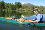 A smiling woman paddling a Chesapeake 17LT wooden kayak on a mountain lake Thumbnail