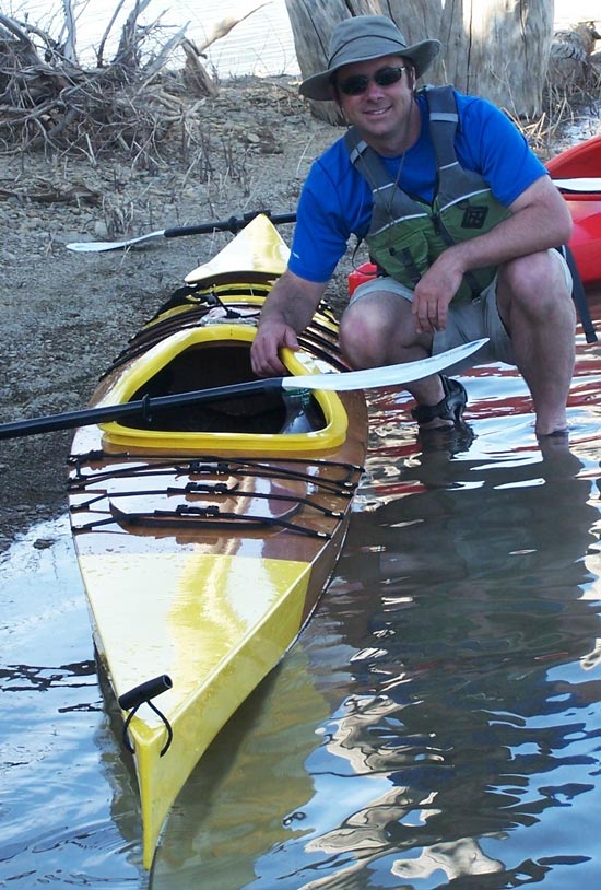 A man and his Chesapeake 17LT wooden kayak at the water's edge