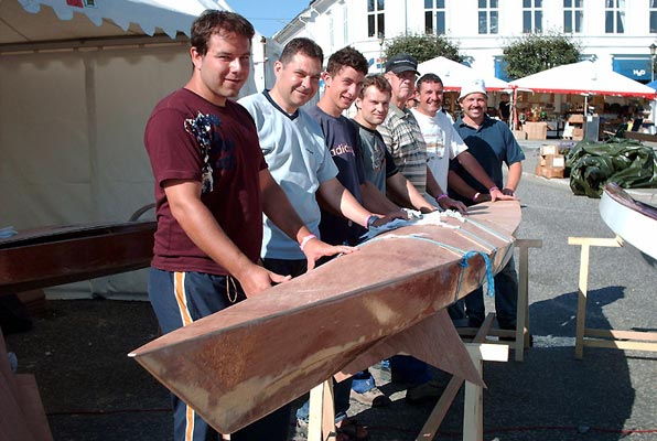 Teamwork! A group of young men and their coach with a Chesapeake 17LT wooden kayak in the final stages of construction