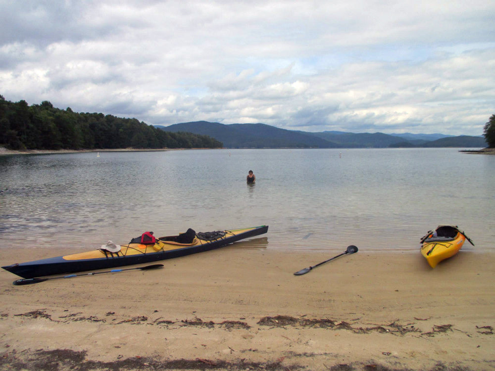 A dark hulled Chesapeake 17LT wooden kayak built by Marilyn B. on a beach at Lake Jocassee, SC