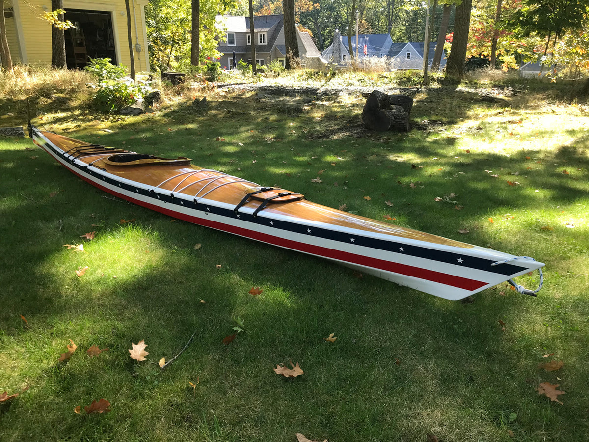 A Chesapeake 17LT wooden kayak with red, white, and blue stripes on the hull, built by Tony O., Cape Elizabeth, ME