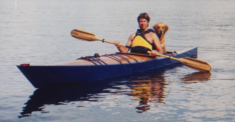 Christopher D. and his dog paddling his Chesapeake 17 wooden kayak