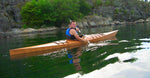 A man paddling a Chesapeake 17 wooden kayak along a rocky coast Thumbnail