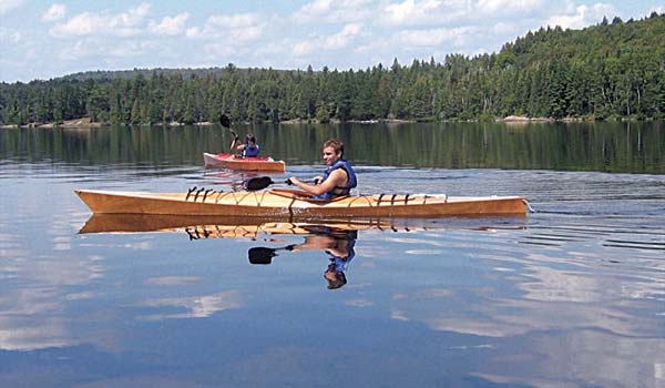 A man paddling a Chesapeake 17 wooden  kayak on a mountain lake