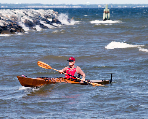 A man paddling a Chesapeake 17 wooden kayak in waves