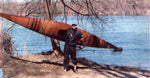 A man carrying a Chesapeake 17 wooden kayak on his shoulder at lakeside Thumbnail