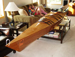 A Chesapeake 17 wooden kayak on a coffee table in a living room with two young girls Thumbnail