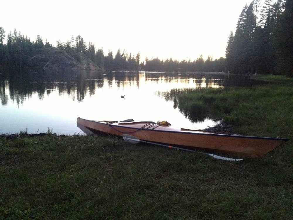 A Chesapeake 17 wooden kayak built by Greg G. pulled up on the grassy bank of Rucker Lake in California