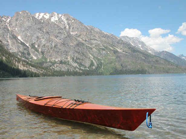 A Chesapeake 17 wooden kayak built by Brandt E. floating on a moutain lake