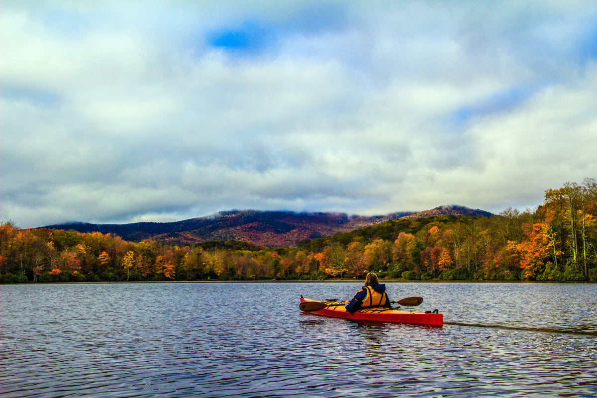 A woman paddling a Chesapeake 17 wooden kayak built by Charles P. on Price Lake on the Blue Ridge Parkway
