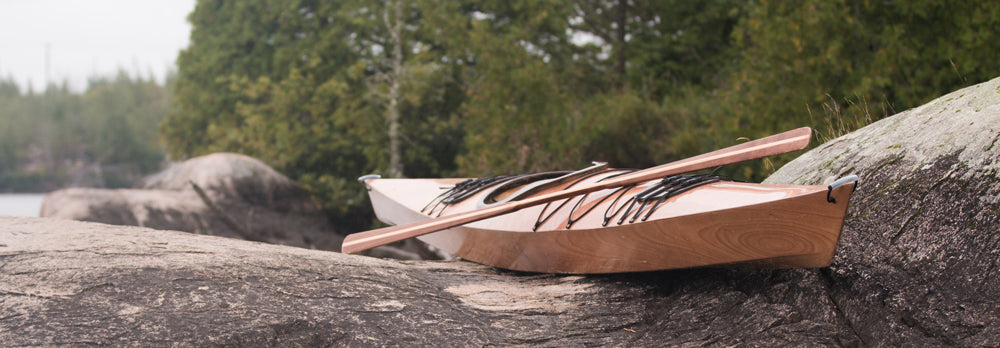 A Chesapeake 17 wooden kayak built from plans by Daniel H. on rocks near an inlet