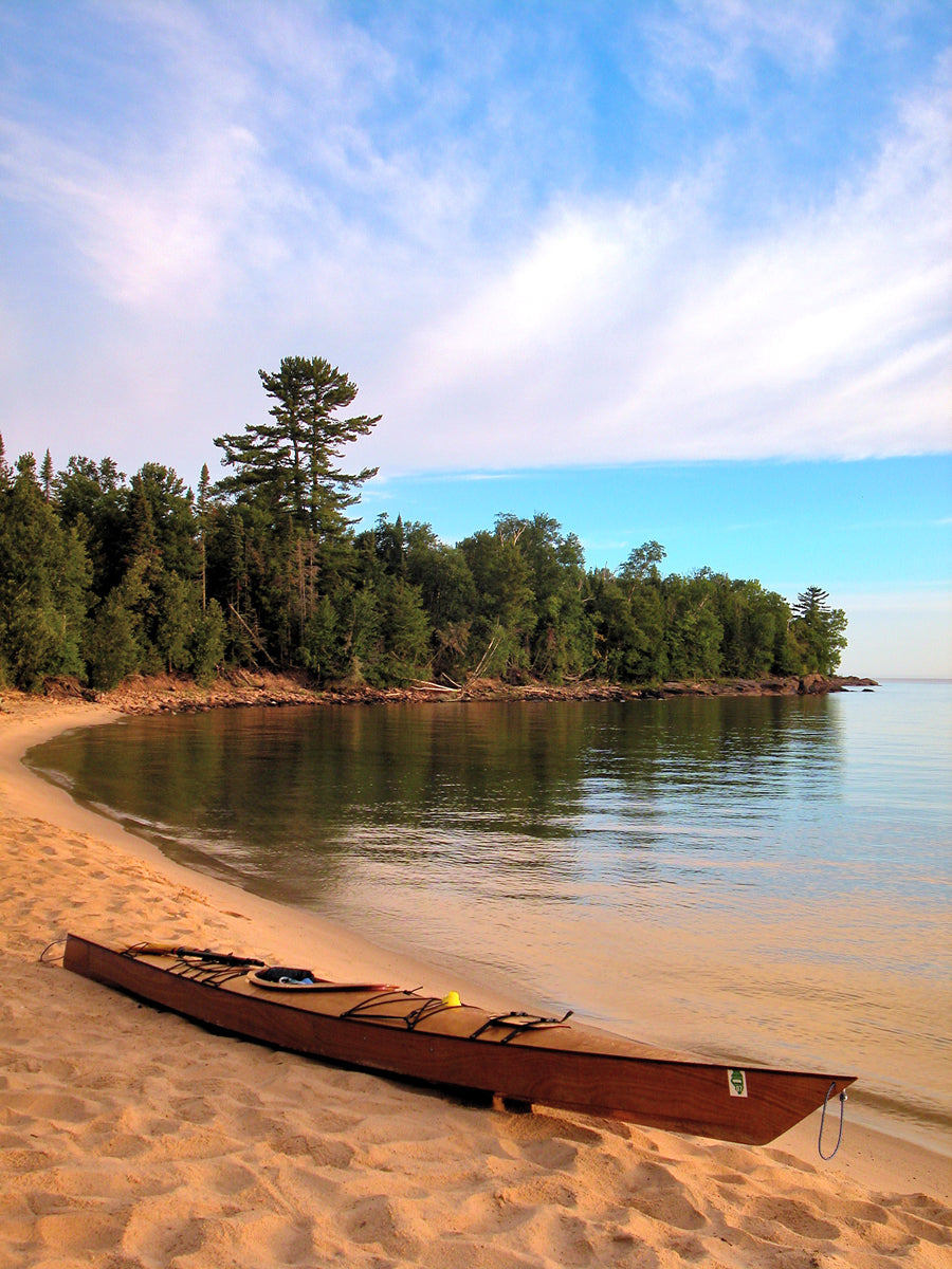 A Chesapeake 17 wooden kayak built by Stan K. on a scenic sandy shore