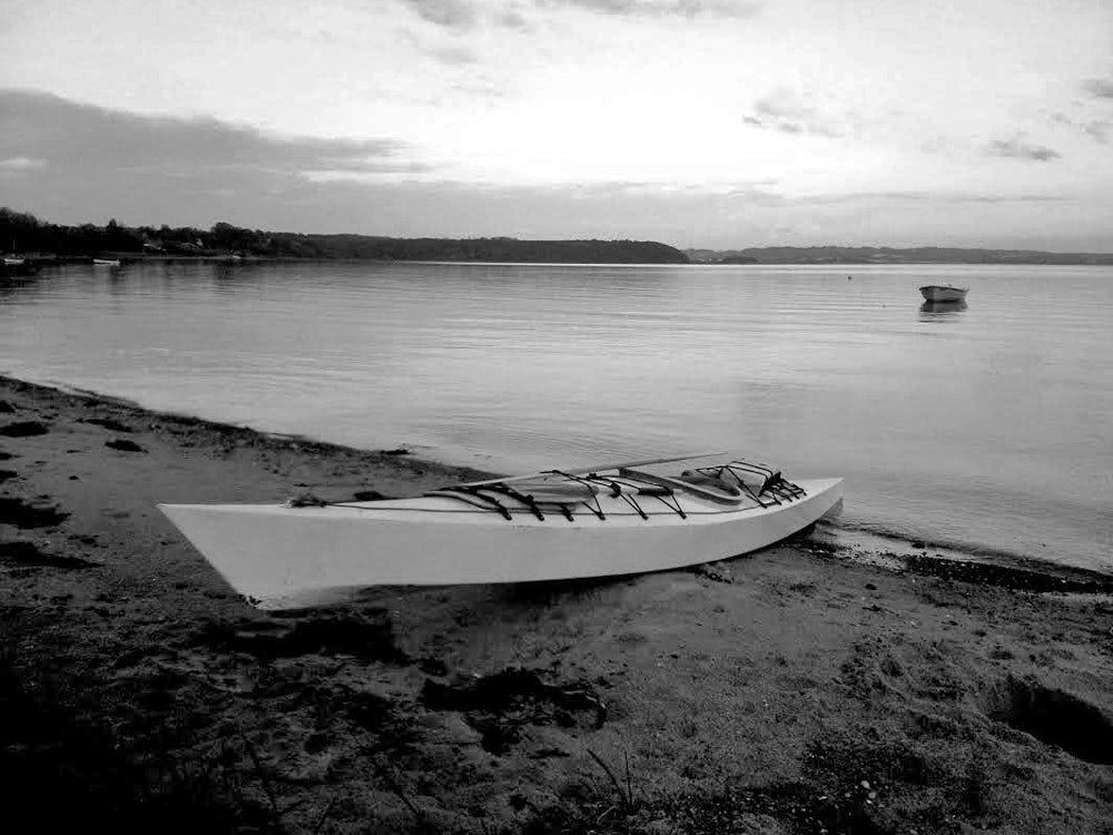 A striking black and white image of a Chesapeake 17 wooden kayak built by Thomas H. on a beach in Denmark