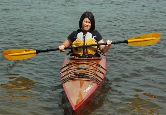 A woman paddling a Chesapeake 17 wooden kayak