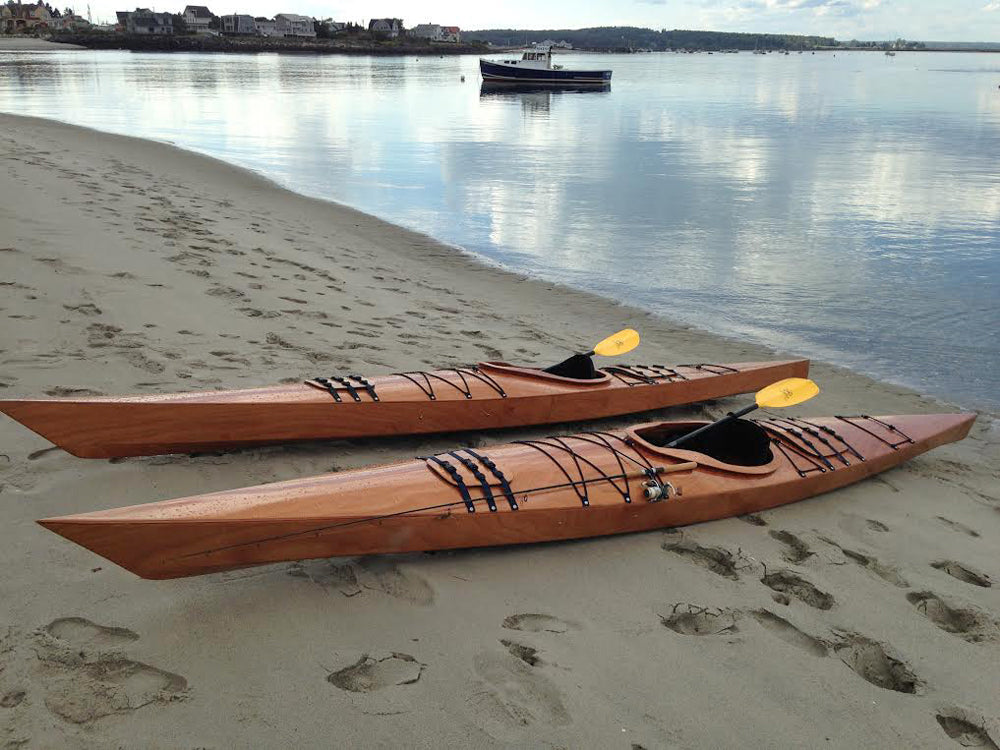 A pair of Chesapeake 17 wooden kayaks built by Mike D. on a sandy beach near Portland, Maine