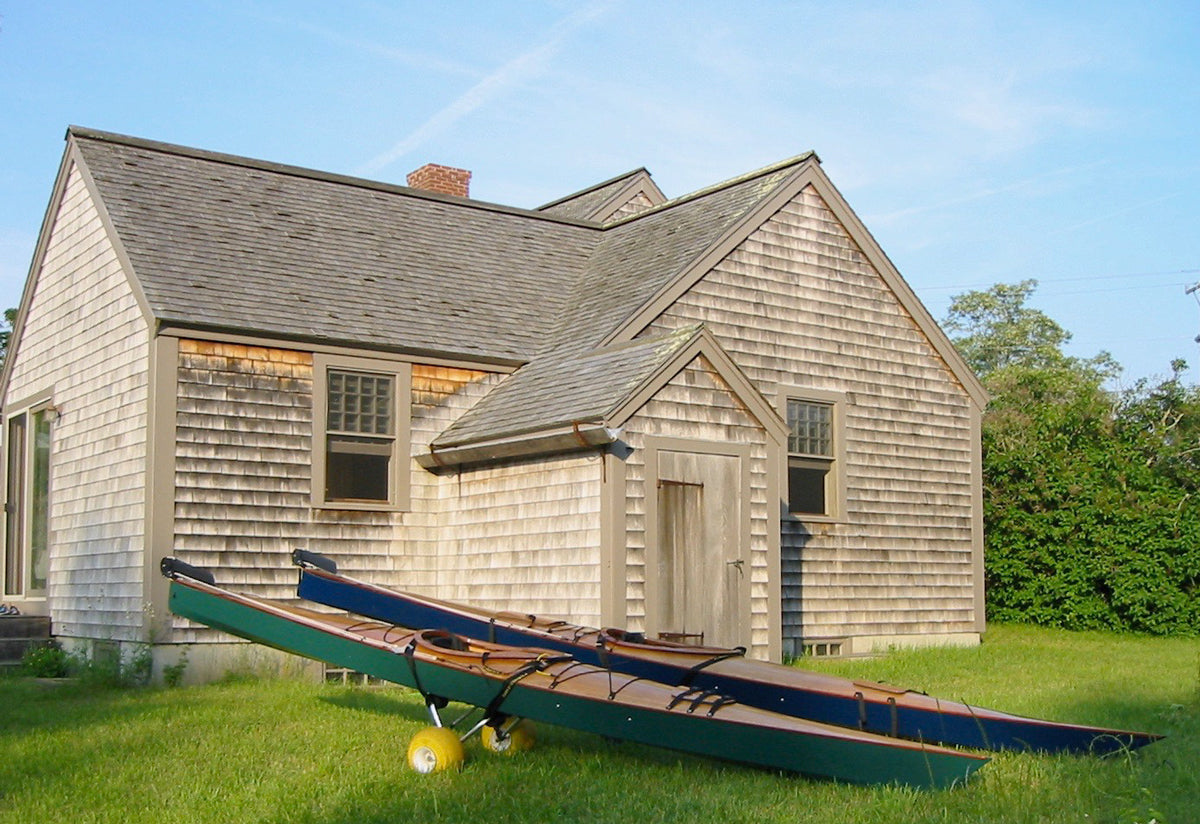 Chesapeake 17 an Pax 18 wooden kayaks built by Randall S. on dollies on a lawn on Martha's Vineyard