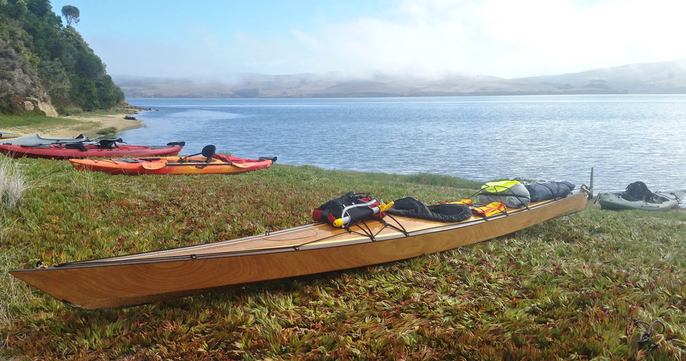 A Chesapeake 18 hybrid wooden kayak built by Mike J. loaded for camping on the lake shore
