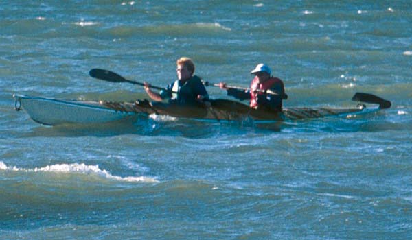 A couple paddling a Chesapeake Double wooden kayak in rough water